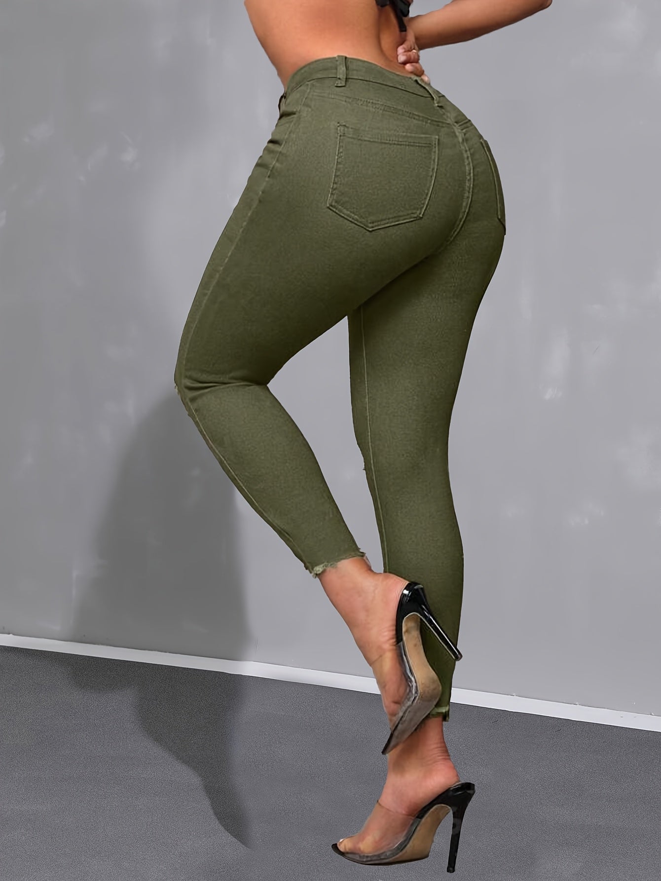 Calça skinny verde militar de cintura alta, moderna e versátil, com detalhes desgastados nas bordas.